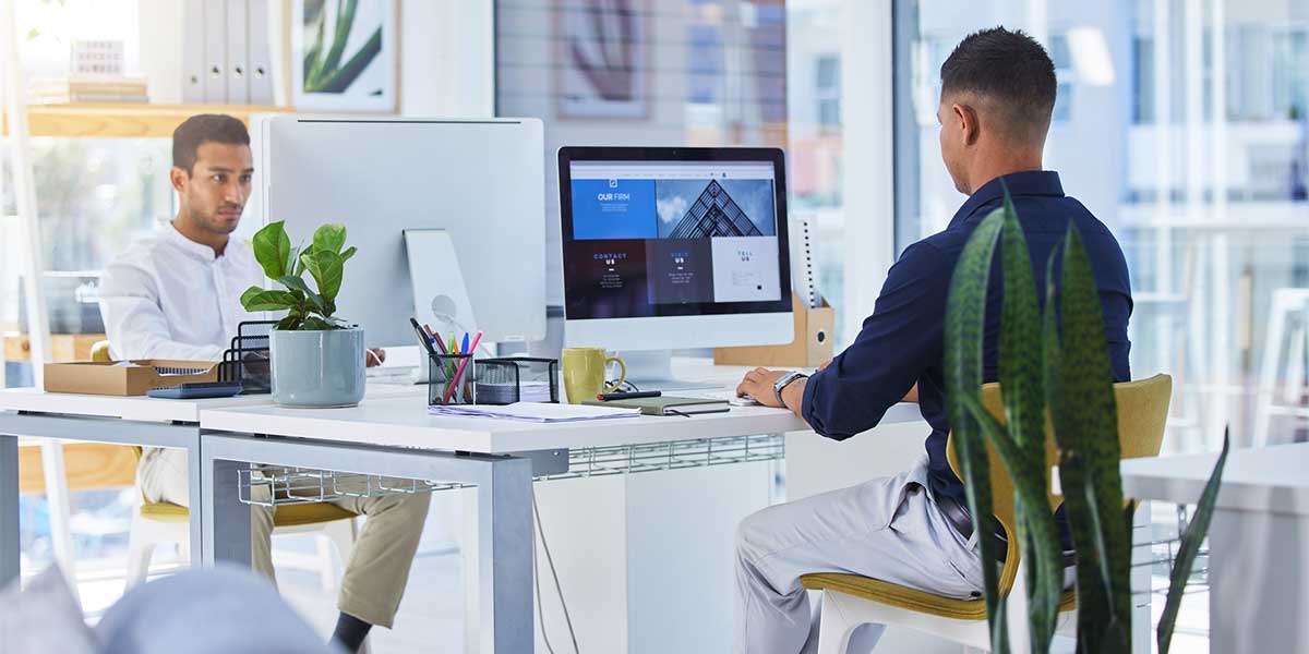 2 men sitting in office and working on web designs