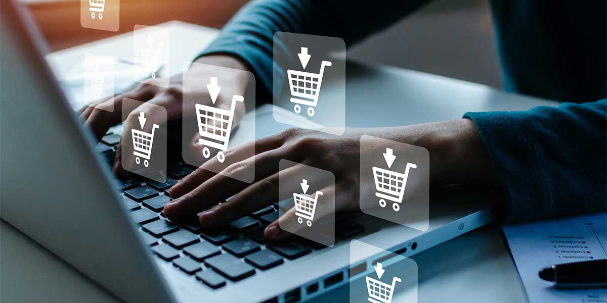person types on computer while shopping cart icons float above
