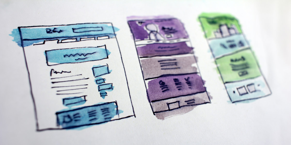 Three website sketches on paper: one with a minimalist design, another with vibrant colors, and a third with a clean and professional layout.