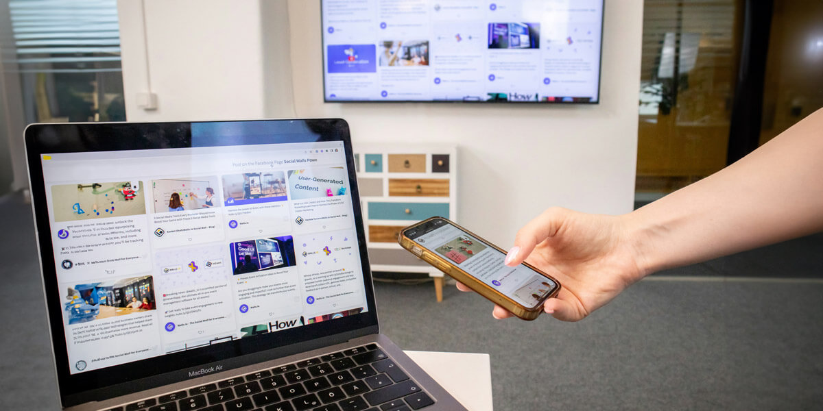 A modern workspace showing a laptop, smartphone, and large wall display all showcasing the same digital content. The setup highlights responsive web design, where layouts adapt seamlessly across multiple devices.
