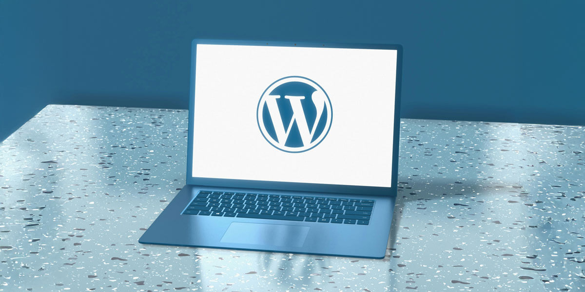 A laptop displaying the WordPress logo sits on a modern desk, representing website architecture and content management technology.