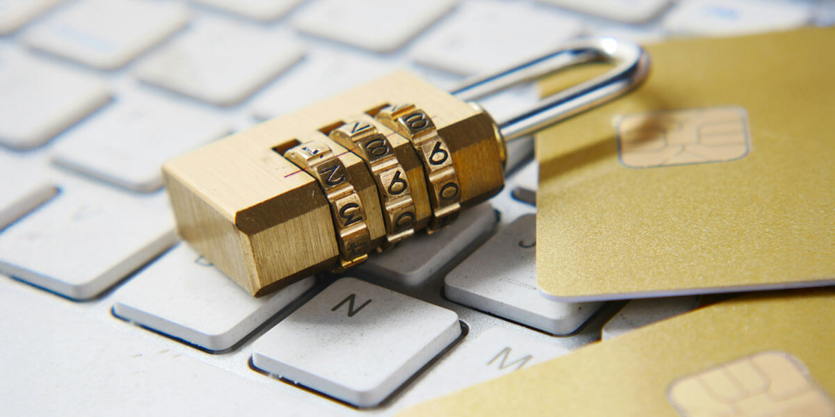 A combination lock and credit cards rest on a computer keyboard, representing website security and data protection.