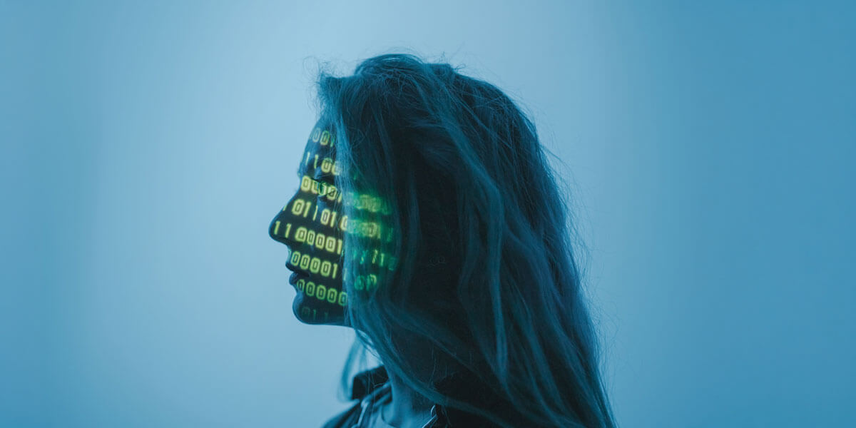 Profile silhouette of a woman with binary code projected across her face against a blue background.